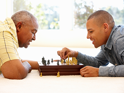 elderly man playing chess against young man