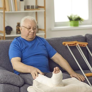 elderly man sitting on a couch with a broken leg