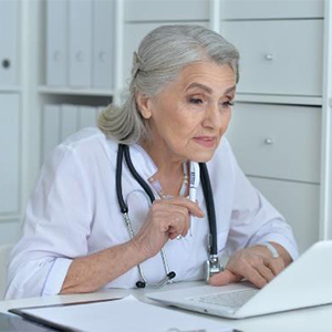 older woman doctor looking at a laptop screen