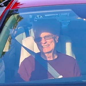 Elderly man sitting in passenger seat of a car.