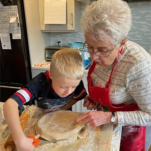 Marti cutting a pie crust with grand kid