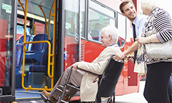 man helping elderly man onto bus