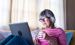 woman using laptop drinking from a mug